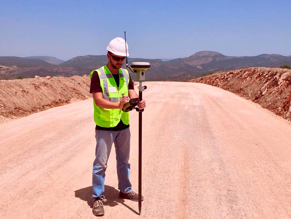 Topógrafo operando equipo GNSS RTK en terreno rural